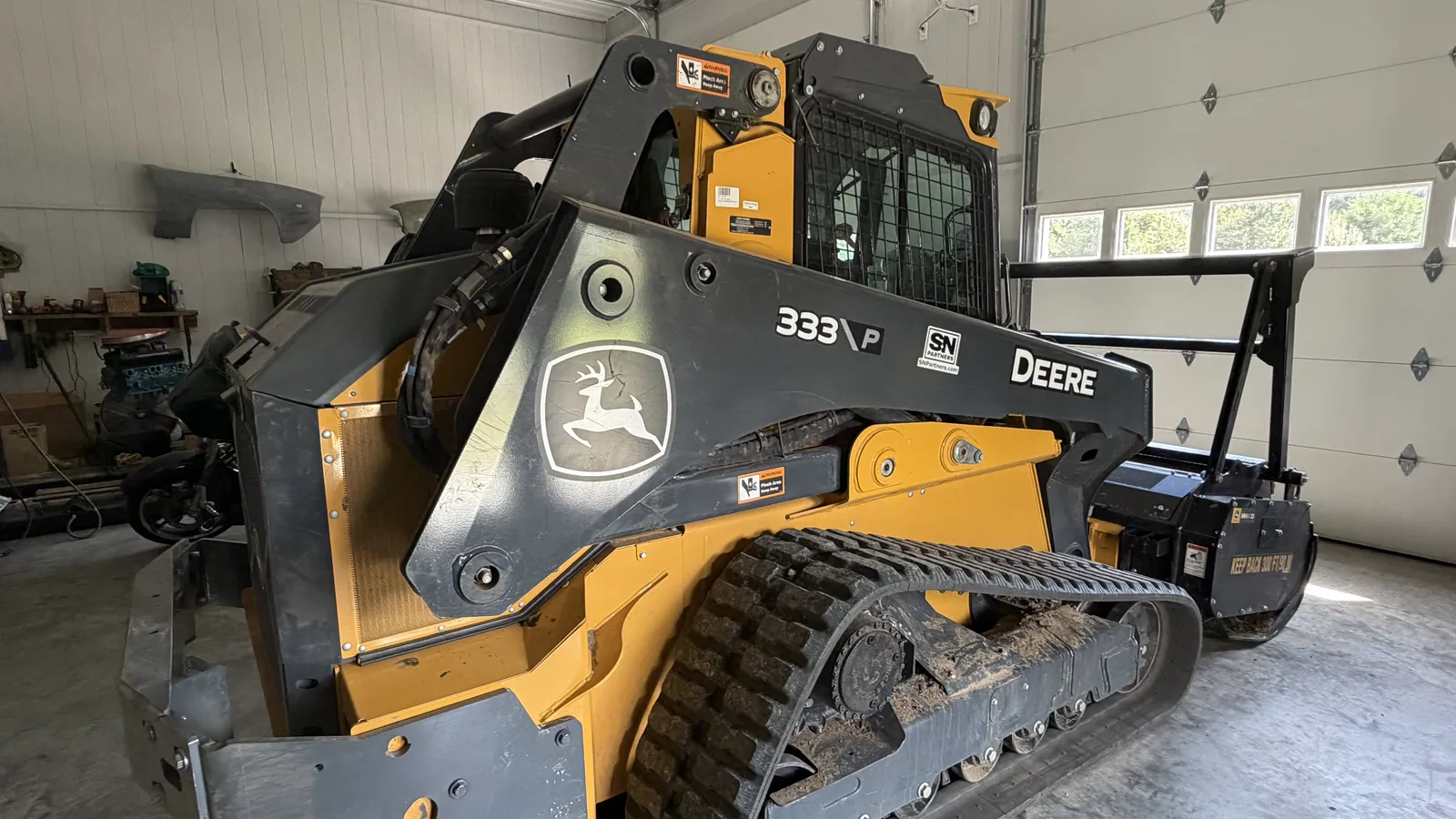 The Mid Missouri Forestry Mulching Deere 333P track loader with mulching head in the shop