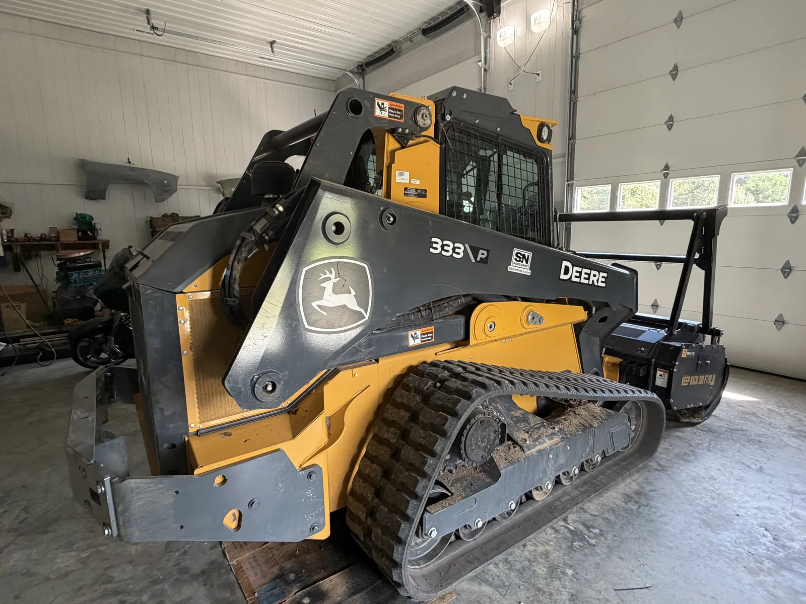 Rear view of the John Deere 333P track loader with mulching head attached