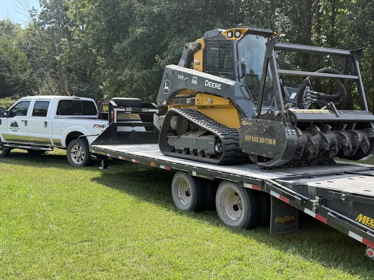Forestry mulcher loaded on a gooseneck trailer behind the company truck