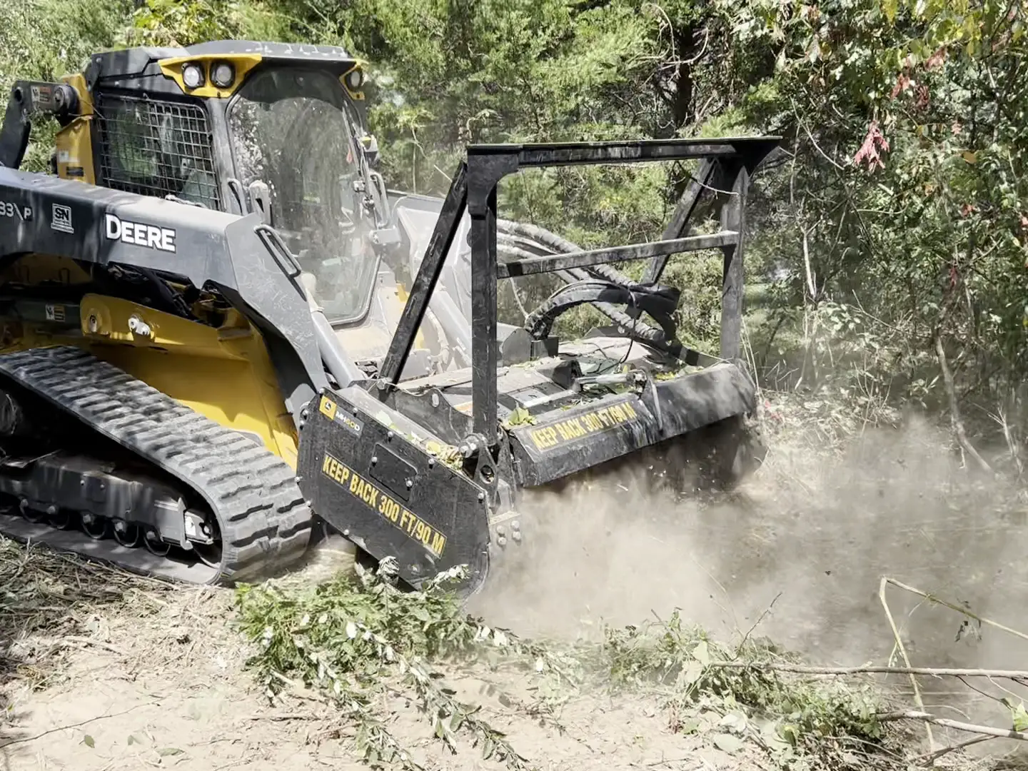 Forestry mulcher grinding cedar and brush in a cloud of dust