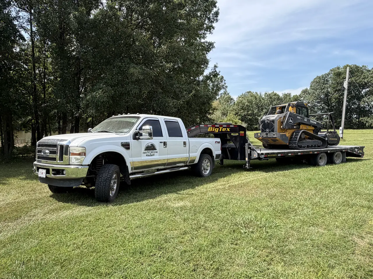 Mid Missouri Forestry Mulching pickup hitched to a gooseneck trailer carrying the Deere 333P mulcher