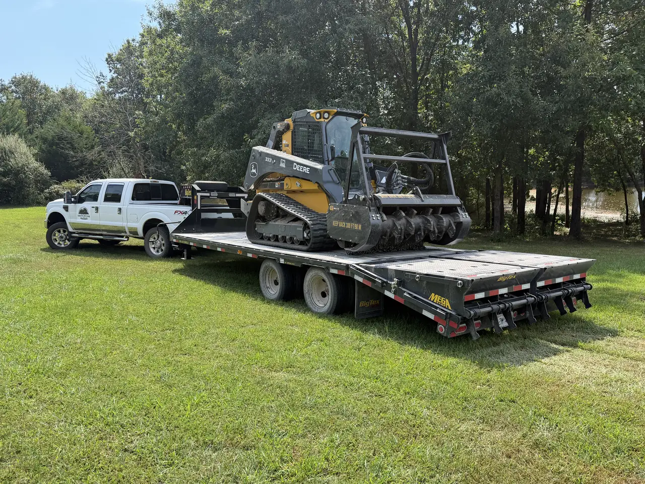 Deere 333P forestry mulcher chained down on a Big Tex gooseneck trailer