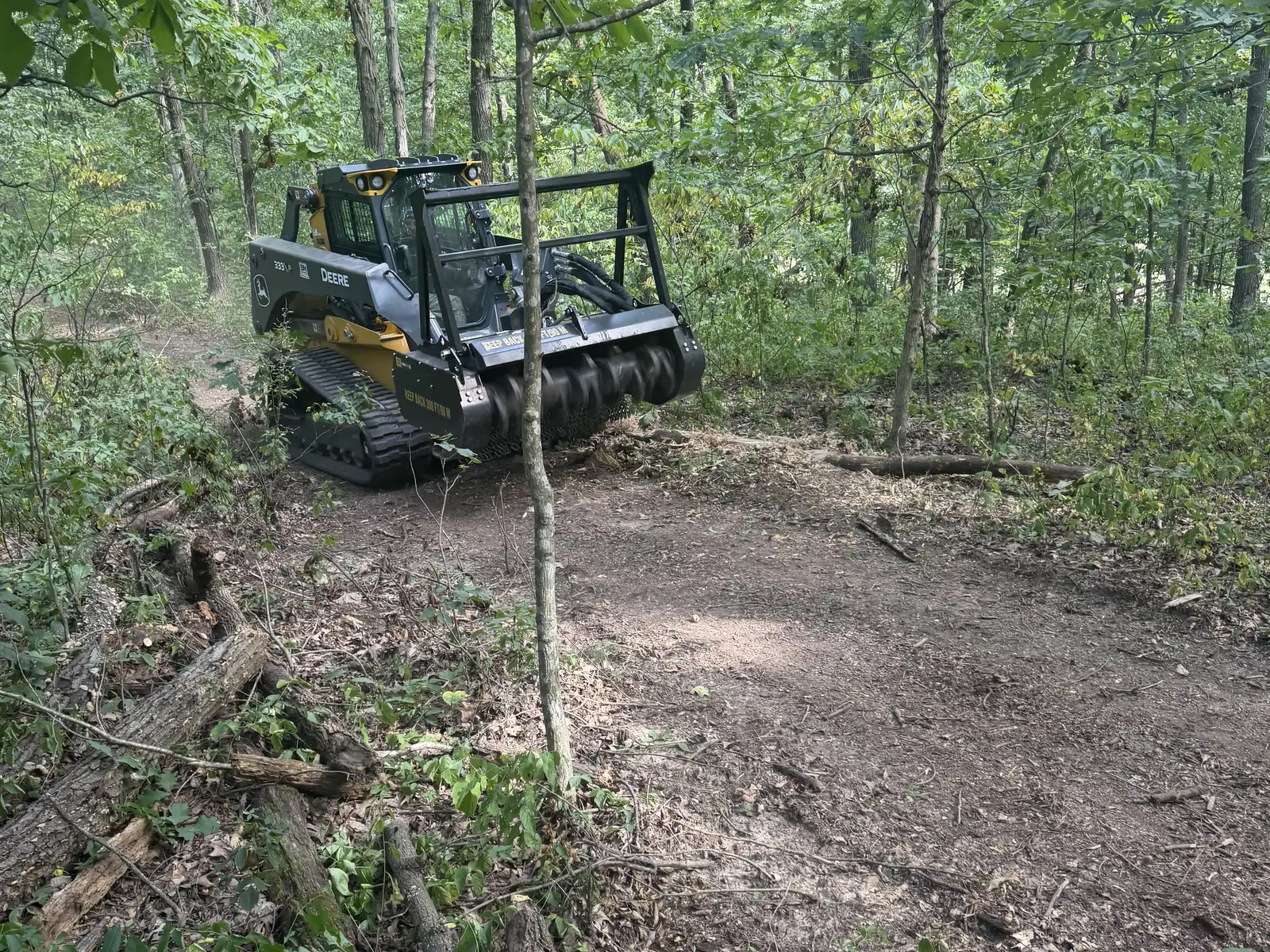 Deere 333P forestry mulcher opening a trail through hardwood timber
